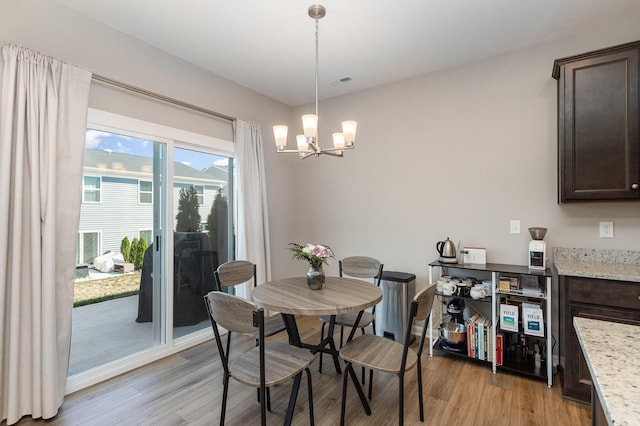 dining room with light wood-type flooring and an inviting chandelier