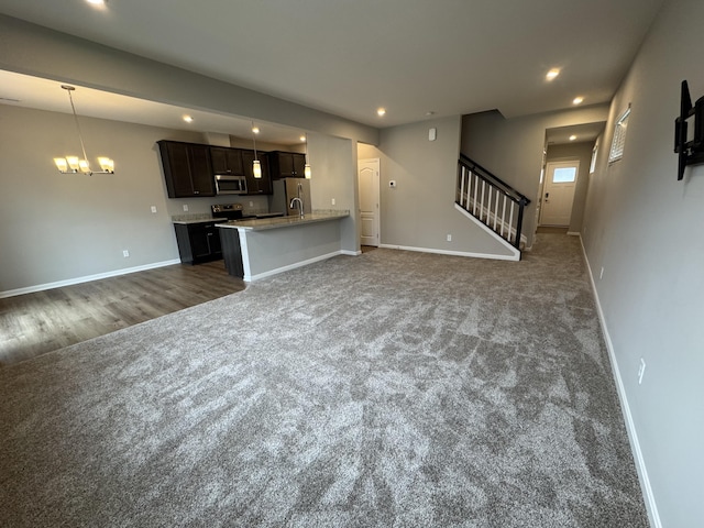 unfurnished living room with an inviting chandelier and dark carpet