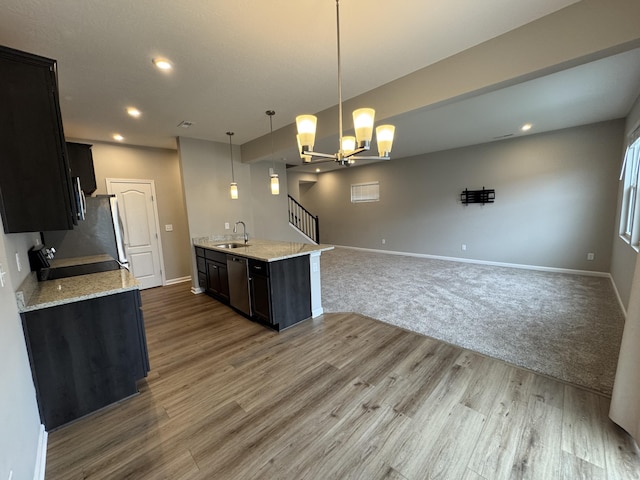 kitchen featuring dishwasher, a chandelier, hanging light fixtures, light stone counters, and sink