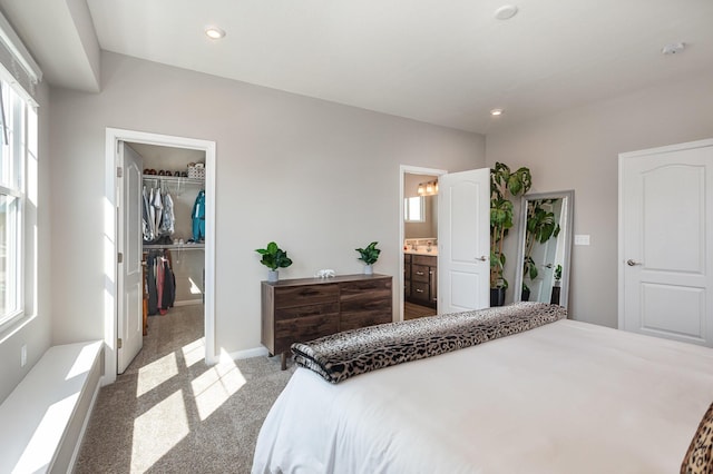 carpeted bedroom featuring a spacious closet, a closet, and ensuite bath