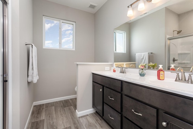 bathroom with toilet, vanity, a shower with shower door, and hardwood / wood-style floors