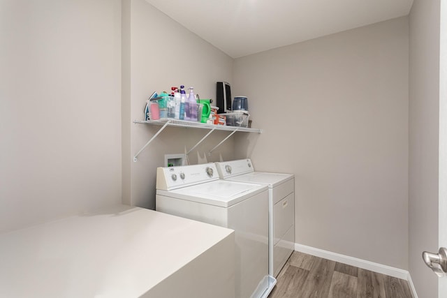 clothes washing area featuring light wood-type flooring and washer and clothes dryer