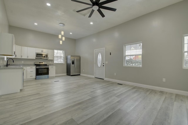 kitchen featuring a high ceiling, white cabinets, appliances with stainless steel finishes, decorative light fixtures, and ceiling fan