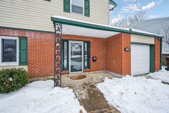 snow covered property entrance featuring a garage