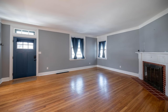 unfurnished living room featuring crown molding, a brick fireplace, and a healthy amount of sunlight