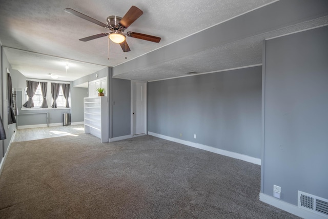 unfurnished living room with ceiling fan, carpet floors, and a textured ceiling