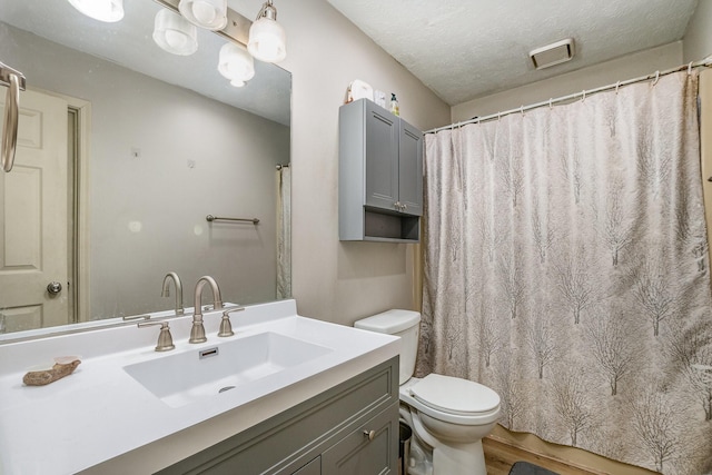 bathroom featuring vanity, toilet, hardwood / wood-style floors, and a textured ceiling