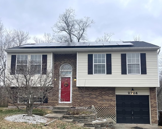 split foyer home featuring a garage and solar panels