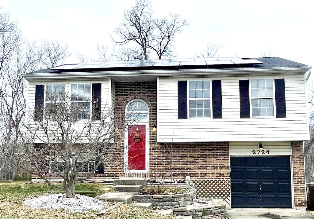 split foyer home featuring a garage and solar panels