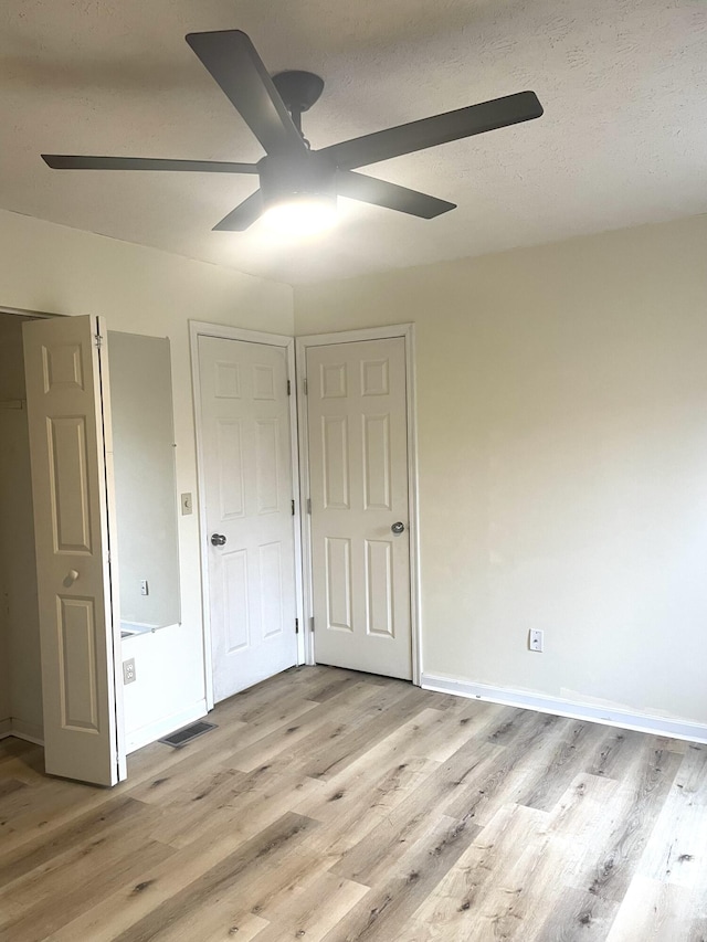 unfurnished bedroom with a textured ceiling, light hardwood / wood-style flooring, and ceiling fan