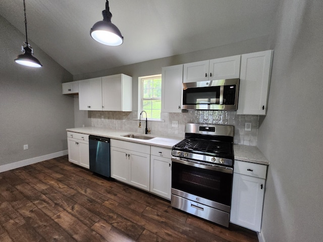 kitchen featuring pendant lighting, white cabinets, appliances with stainless steel finishes, sink, and vaulted ceiling