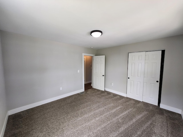 unfurnished bedroom featuring a closet and dark carpet