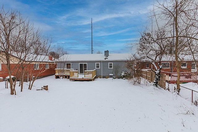 snow covered rear of property with a deck