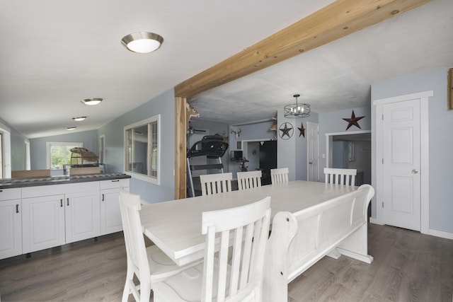 dining space featuring vaulted ceiling, dark wood-type flooring, and an inviting chandelier