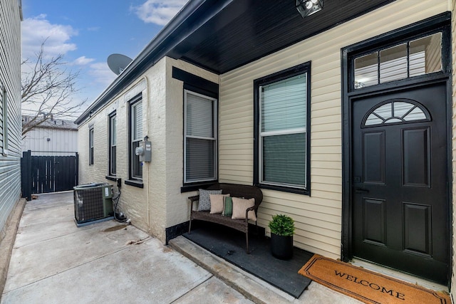 view of exterior entry with a porch and central AC