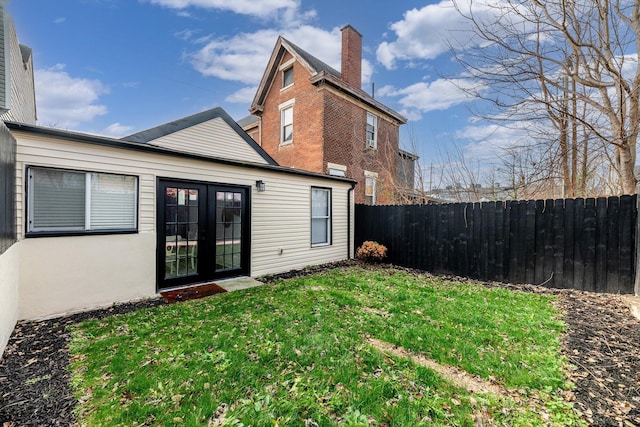 rear view of property with a lawn and french doors