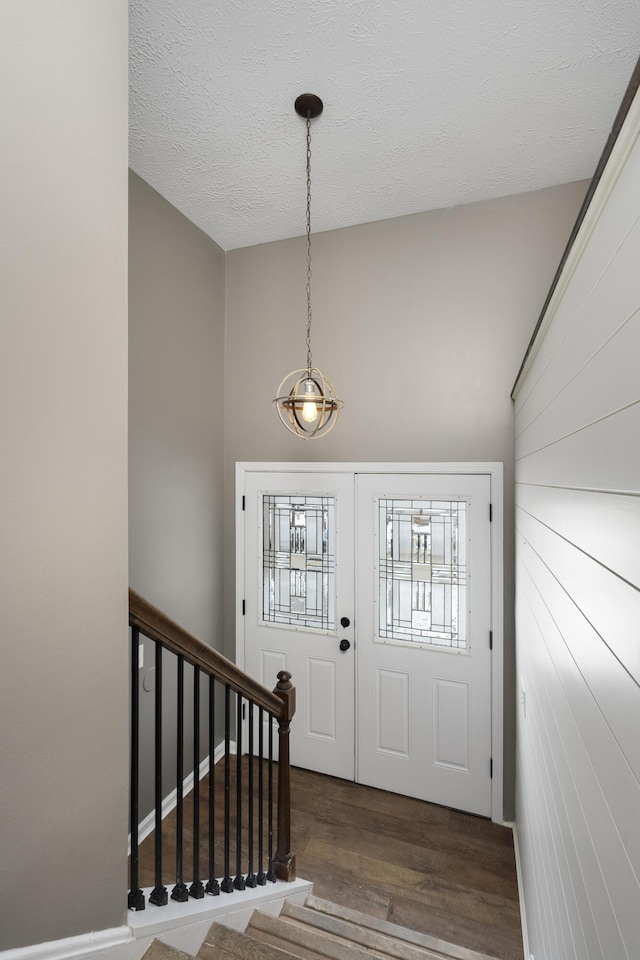 foyer entrance featuring dark wood-type flooring, a textured ceiling, and vaulted ceiling