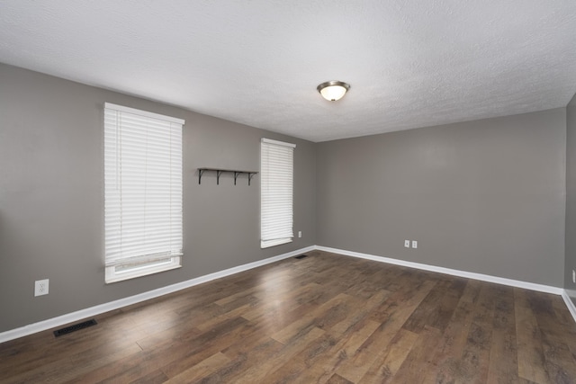 empty room with dark hardwood / wood-style floors and a textured ceiling