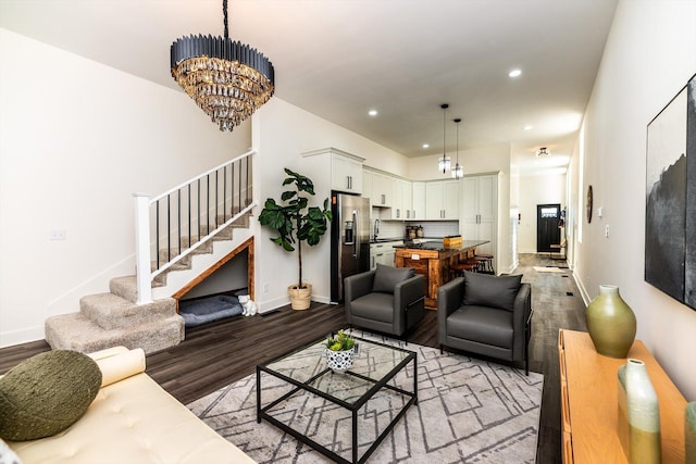 living room featuring wood-type flooring, sink, and an inviting chandelier