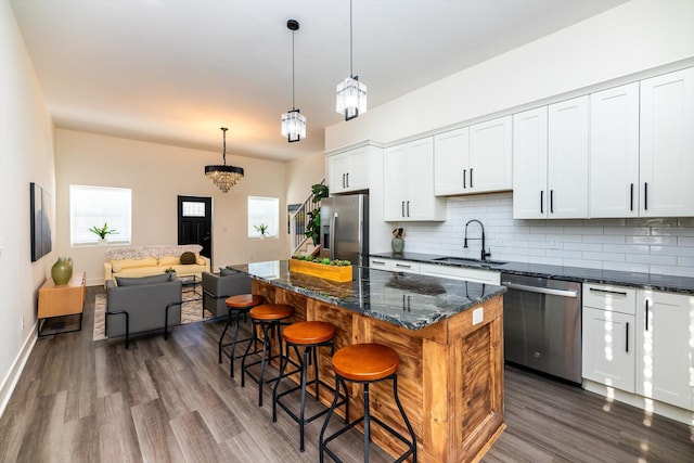 kitchen featuring white cabinets, appliances with stainless steel finishes, a kitchen island, sink, and hanging light fixtures