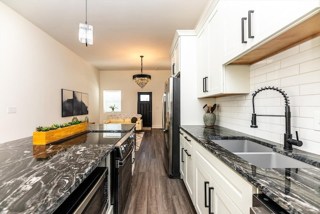 kitchen featuring white cabinets, sink, dark stone countertops, and stainless steel refrigerator