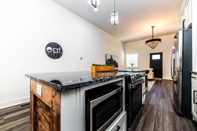 kitchen featuring a kitchen island, hanging light fixtures, appliances with stainless steel finishes, white cabinets, and dark stone counters