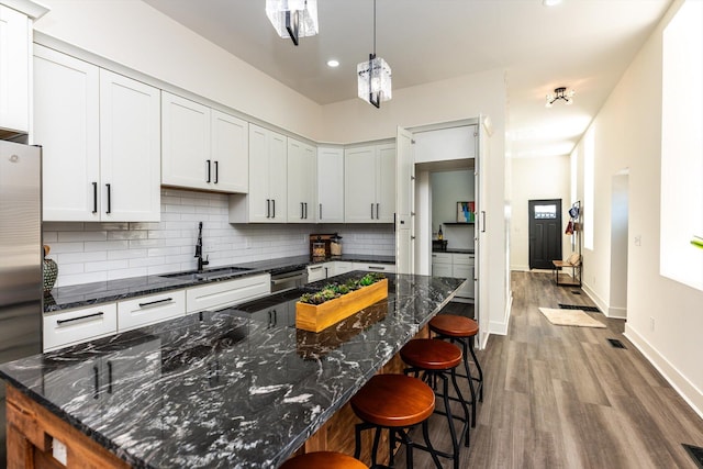 kitchen featuring sink, white cabinetry, stainless steel appliances, and dark stone countertops