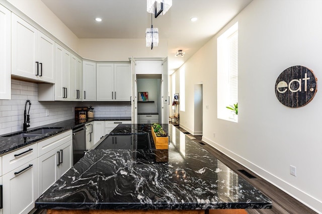 kitchen with white cabinetry, dark stone countertops, and dishwasher