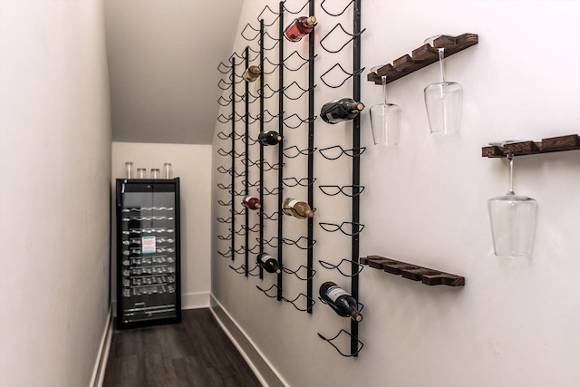 wine room with vaulted ceiling, dark hardwood / wood-style flooring, and beverage cooler