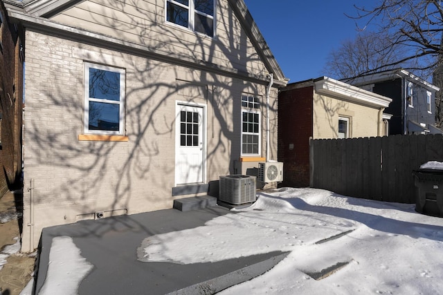 snow covered house with central AC unit and ac unit