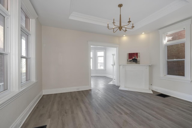 unfurnished dining area featuring hardwood / wood-style floors, ornamental molding, a raised ceiling, and an inviting chandelier