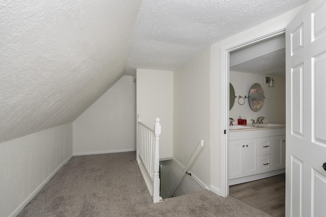 interior space featuring a textured ceiling, vaulted ceiling, light carpet, and sink