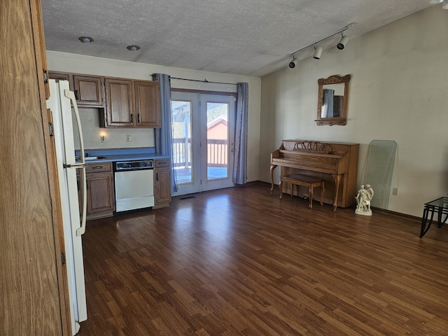 kitchen featuring track lighting, white appliances, dark hardwood / wood-style floors, and a textured ceiling