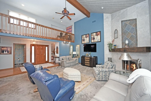 carpeted living room featuring ceiling fan, a high end fireplace, beam ceiling, and high vaulted ceiling