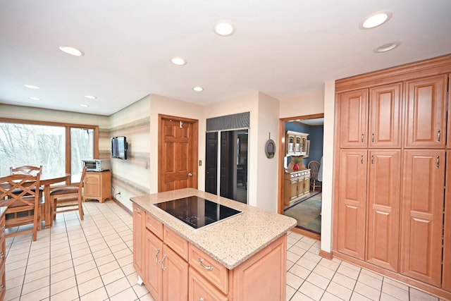 kitchen with light stone countertops, a center island, black electric stovetop, and light tile patterned floors