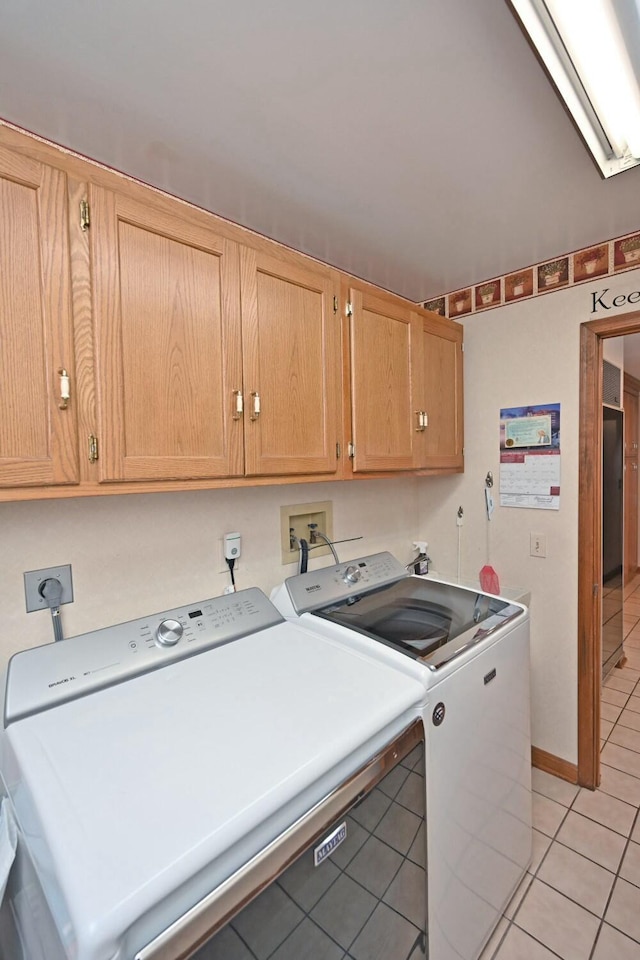 washroom featuring independent washer and dryer, cabinets, and light tile patterned floors