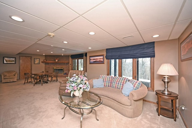 carpeted living room with a brick fireplace and a drop ceiling