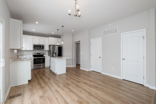 kitchen featuring pendant lighting, sink, stainless steel appliances, a center island, and white cabinets