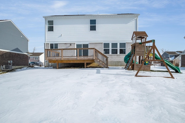 snow covered house featuring a playground, a wooden deck, and central AC