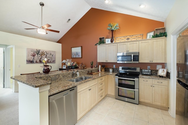 kitchen featuring appliances with stainless steel finishes, sink, high vaulted ceiling, kitchen peninsula, and dark stone counters