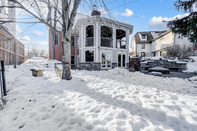 snow covered back of property featuring french doors