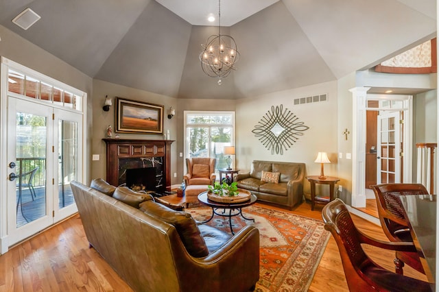 living room featuring a healthy amount of sunlight, an inviting chandelier, a high end fireplace, and light hardwood / wood-style floors