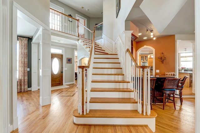 stairway with a high ceiling, hardwood / wood-style floors, and ornate columns