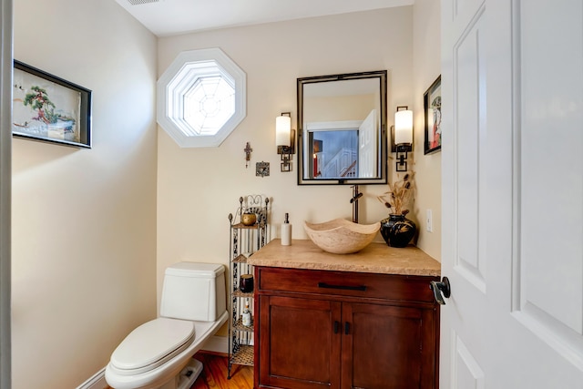 bathroom featuring toilet, vanity, and hardwood / wood-style floors