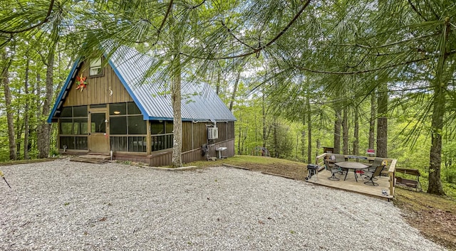 rear view of house with central AC unit and a sunroom