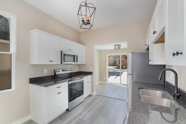 kitchen featuring stainless steel appliances, decorative light fixtures, white cabinets, light hardwood / wood-style flooring, and sink