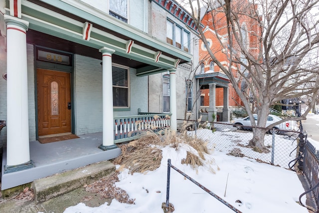 snow covered property entrance with covered porch