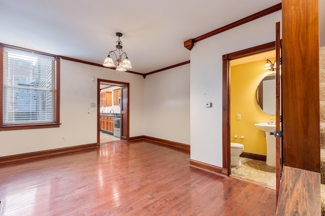 empty room with hardwood / wood-style floors, crown molding, and an inviting chandelier