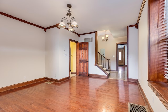 unfurnished room with a chandelier, ornamental molding, and hardwood / wood-style floors