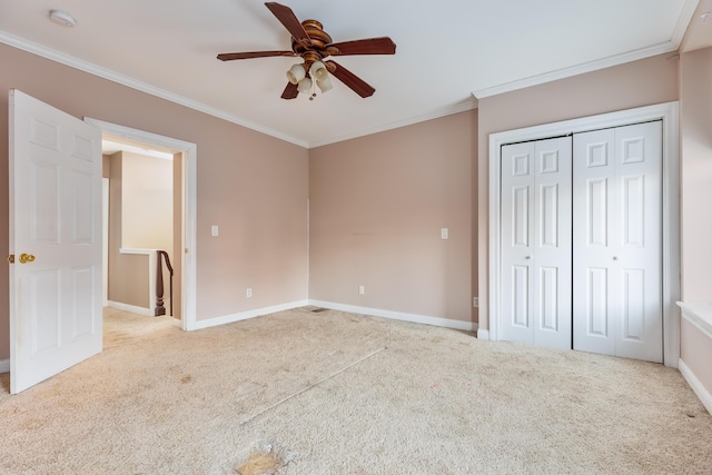 unfurnished bedroom featuring ceiling fan, light colored carpet, a closet, and ornamental molding